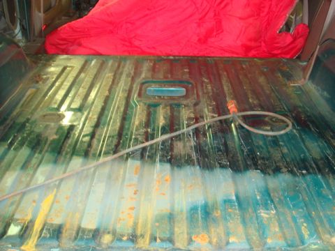 1996 Ford Bronco - The interior floor of a truck bed shows signs of rust and wear, covered partially by a red tarp.