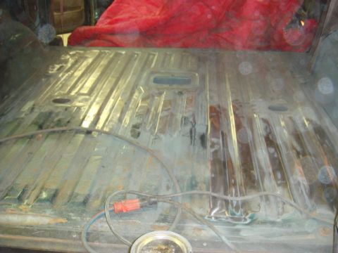 1996 Ford Bronco - The interior floor of a vehicle shows signs of rust and repair work, with electrical cords present.