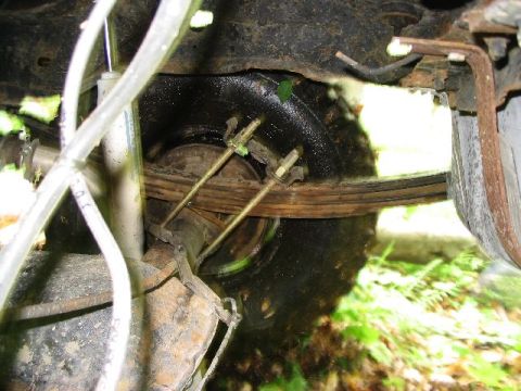 1986 Ford Bronco - Close-up view of a vehicle's leaf spring suspension and tire, showing mechanical components.