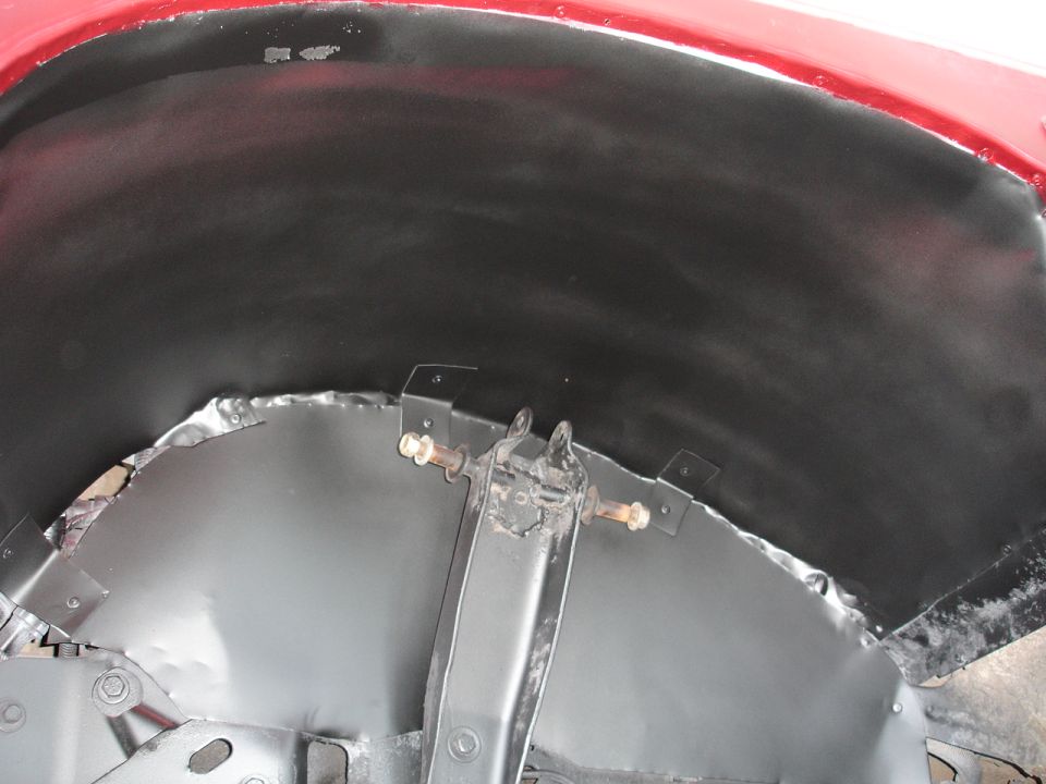 Close-up of a vehicle's inner wheel well, showing metal work and suspension components