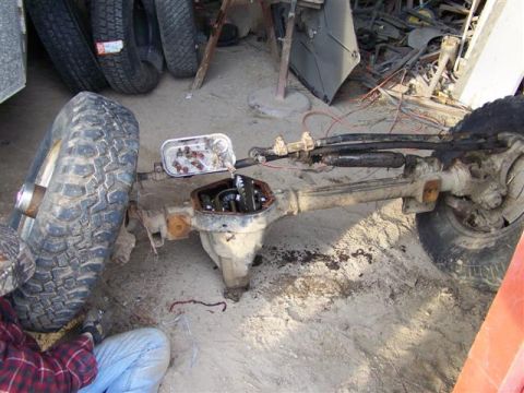 1995 Ford Bronco - A front axle assembly is shown with its differential cover removed, revealing internal gears.