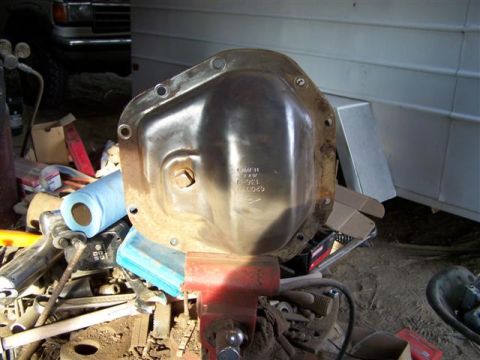 1995 Ford Bronco - Differential cover with visible casting numbers, held in a red vise with tools and a vehicle in the background.