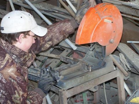 1995 Ford Bronco - A person operates a chop saw amidst a cluttered collection of metal and pipes.