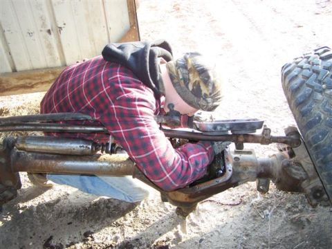 1995 Ford Bronco - A person works on a Dana 60 axle assembly, with a large tire visible in the background.