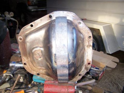 1995 Ford Bronco - Differential cover with a welded brace, clamped in a vise with tools nearby.