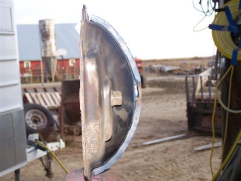 1995 Ford Bronco - A close-up view of a weathered metal component, possibly from a vehicle, with a rural background.