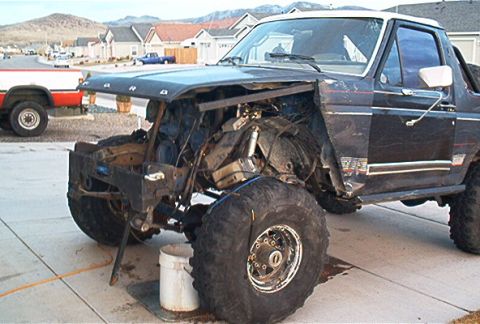 1986 Ford Bronco - Front end of a 1986 Ford Bronco showing damage and exposed engine parts.