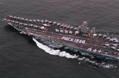 1986 Ford Bronco - An aircraft carrier sails through the ocean, its deck crowded with fighter jets and a provocative message displayed.