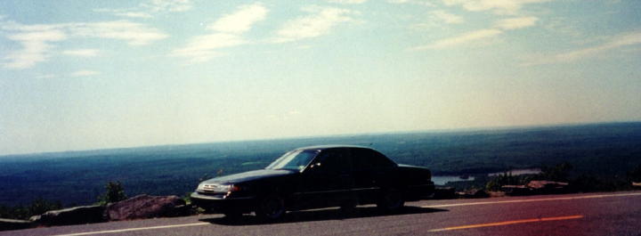 Black sedan parked on roadside, side view. Watermark 'SUPERMOTORS www.supermotors.net' visible