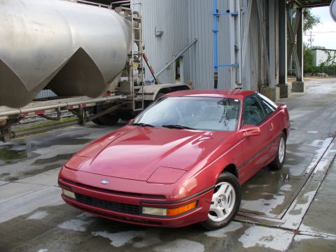 1991 Ford Probe - Front three-quarter view of a freshly washed red Ford Probe hatchback coupe with pop-up headlights closed, amber corner lenses and silver f…