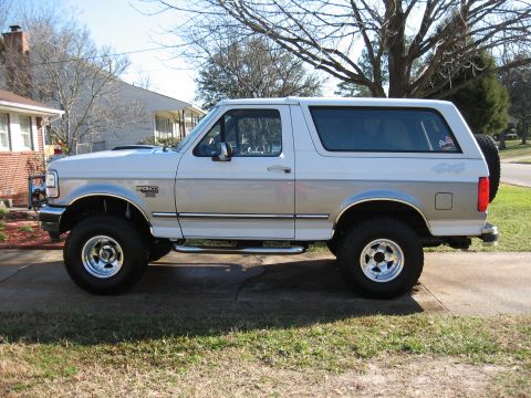 1994 Ford Bronco - This lifted 1994 Ford Bronco features a two-tone paint scheme and is parked in a driveway.