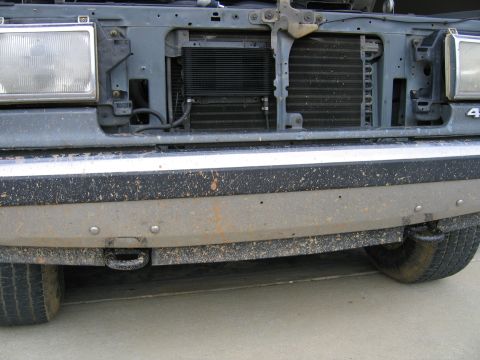 1989 Ford Bronco - The front of a truck shows a tow hook and a dirty bumper with visible mud splatter.