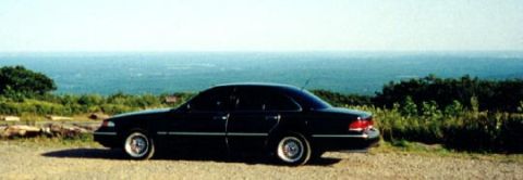 1997 Ford Crown Victoria - Side view of a black 1997 Ford Crown Victoria parked with a scenic ocean backdrop.