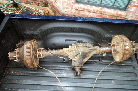 1978 Dodge Power Ram - Rusty rear axle assembly with drum brakes is shown in the bed of a pickup truck.