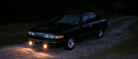 1997 Ford Crown Victoria - 1997 Ford Crown Victoria parked on gravel at night with headlights illuminated.