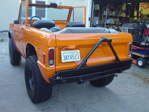 1977 Ford Bronco - This orange 1977 Ford Bronco is shown from the rear, an aftermarket bumper and spare tire carrier.