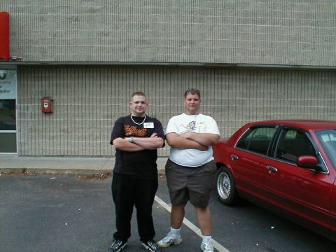 1997 Ford Crown Victoria - A red 1997 Ford Crown Victoria is parked next to two men in front of a brick building.