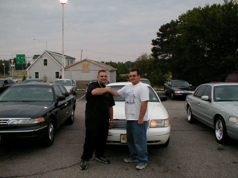 1997 Ford Crown Victoria - Two men shake hands in front of a 1997 Ford Crown Victoria, with several other vehicles visible in the parking lot.