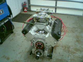1978 Ford Bronco - Engine with dual carburetors and red wiring, on a stand, in a garage.