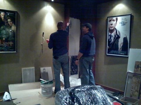 2006 Ford E350 - Two men are working on hanging posters in a room that appears to be under renovation.
