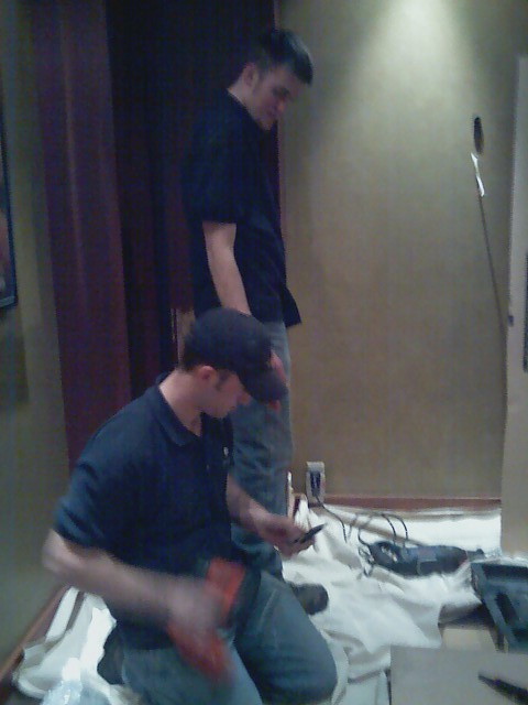 2006 Ford E350 - Two men are seen working indoors on a project, with tools and drop cloths spread out on the floor.
