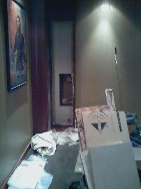 2006 Ford E350 - A dimly lit room shows a movie poster, stacked boxes, and various items on the floor, suggesting a storage or work-in-progress area.