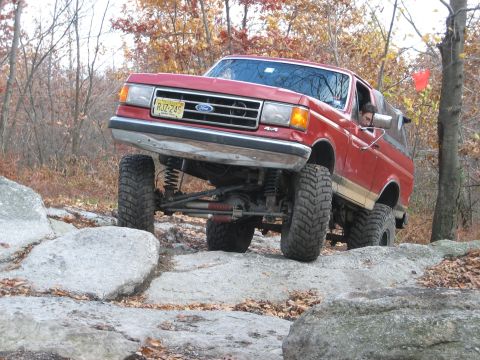 1990 Ford Bronco - This red 1990 Ford Bronco is shown off-roading over large rocks.