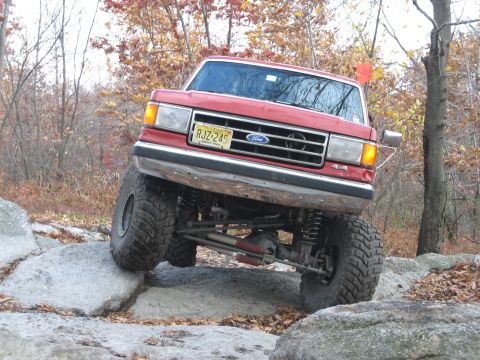 1990 Ford Bronco - This modified Ford Bronco is shown tackling a rocky obstacle on an off-road trail during autumn.