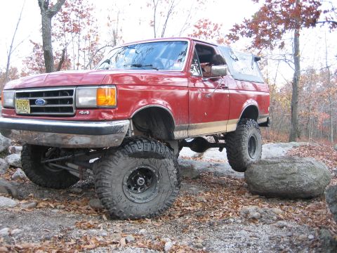 1990 Ford Bronco - This lifted Ford Bronco navigates a rocky trail in a wooded area during autumn.
