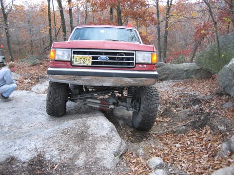 1990 Ford Bronco - Red 1990 Ford Bronco navigating rocky terrain during an off-road excursion.