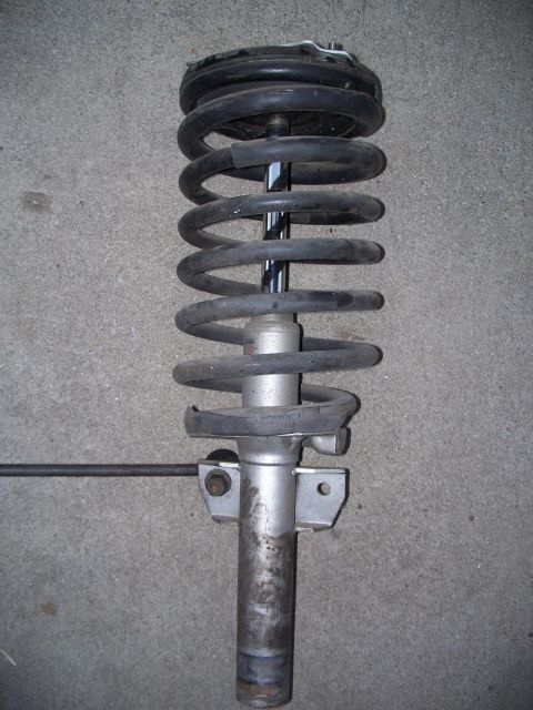 1993 Ford Taurus - A front strut assembly with a coil spring is shown against a concrete background.