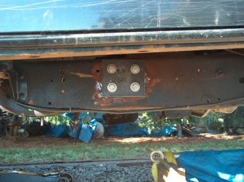 1991 Ford Bronco - Close-up of a bracket bolted to a vehicle's frame, with visible text 'P.S. DOT'.