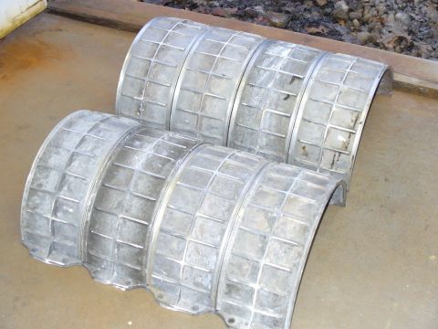 1978 Ford Bronco - Two sets of vintage wheel covers with a distinctive square grid pattern are shown resting on a concrete surface.