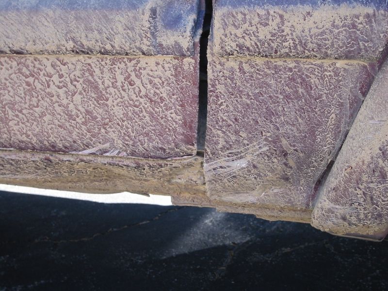 Close-up of dried tan mud and scrapes on a maroon vehicle's rocker panel and door bottom