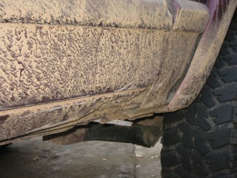 2000 Jeep Cherokee - The lower body and tire of a vehicle are heavily coated in mud.