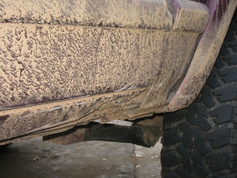 Rocker panel and lower door of a maroon SUV caked in dried tan trail mud