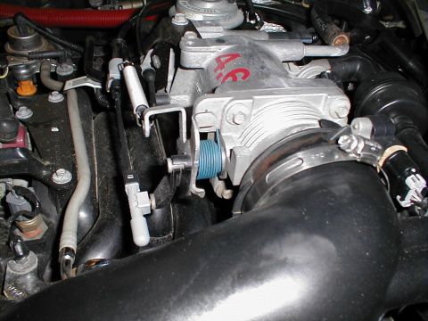 1997 Ford Crown Victoria - Close-up view of an engine's intake manifold, showing a '4.6' marking and a blue throttle cable pulley.