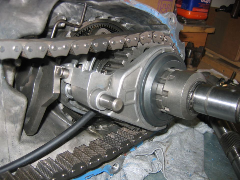 Disassembled transfer case with drive chain, sprockets and output shaft on a workbench