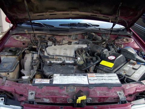 1992 Ford Taurus - The engine bay of a 1992 Ford Taurus, revealing its V6 engine and associated components under the open hood.