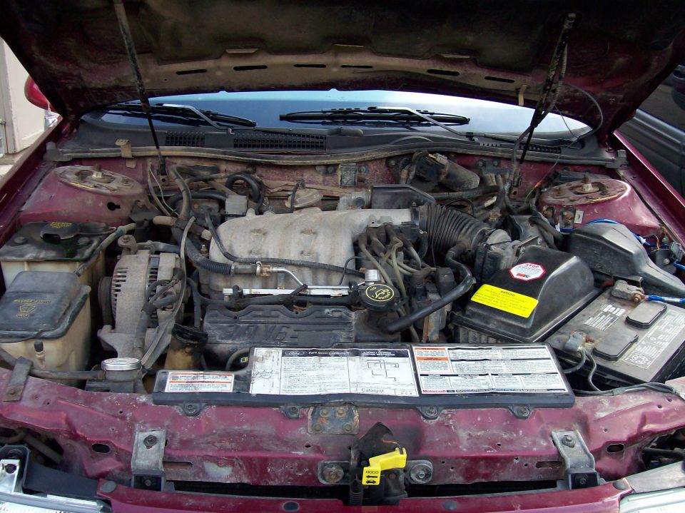 Maroon 1992 Ford Taurus engine bay with hood open, showing V6 engine, battery, and various hoses