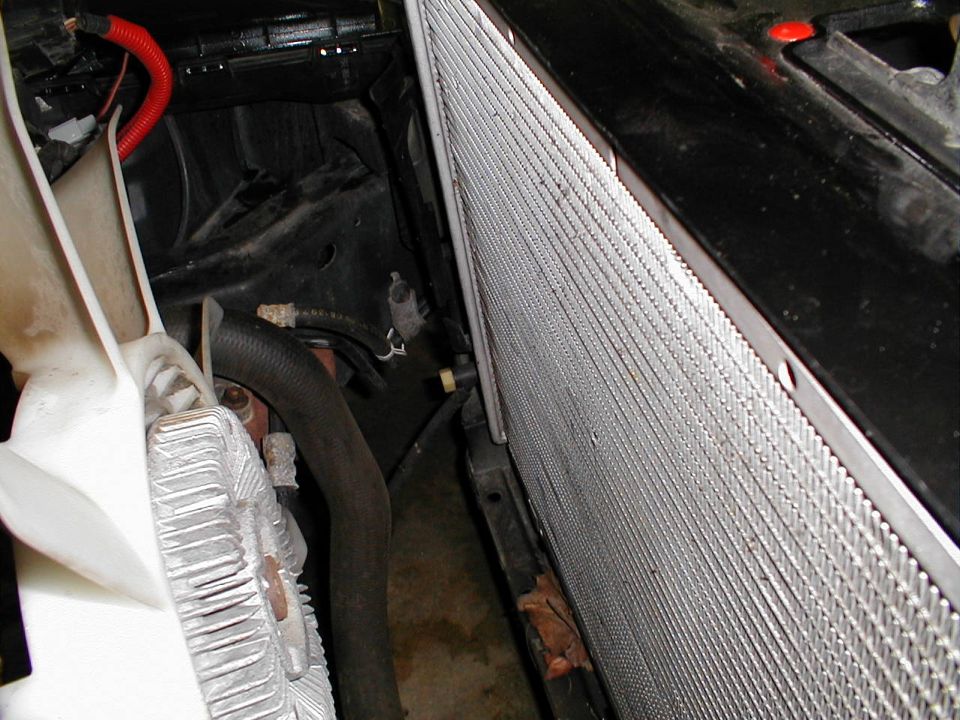 Radiator and fan shroud in engine bay. Supermotors.net logo visible