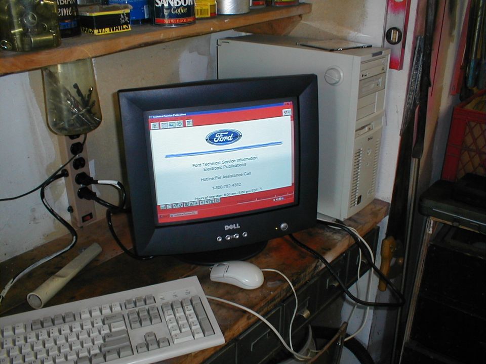 Computer monitor displaying Ford Technical Service Information, with keyboard and mouse