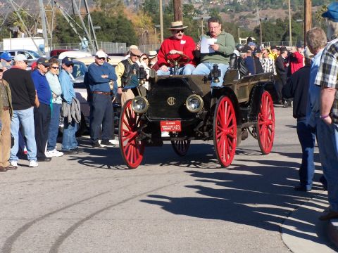 1990 Ford Bronco - An antique car with bright red wheels is on display, with spectators gathered around.