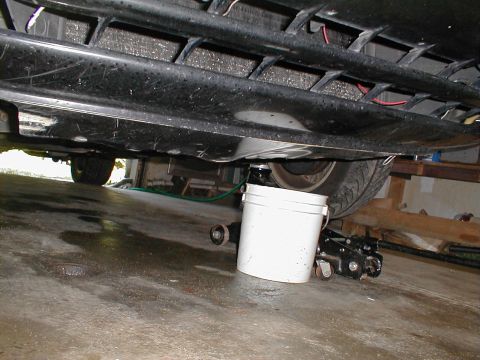 1997 Ford Crown Victoria - The underside of a vehicle is shown with a bucket and jack, suggesting maintenance work is in progress.