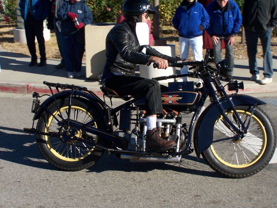 Black vintage motorcycle with yellow-rimmed wheels, rider in leather jacket