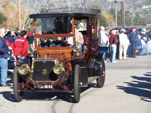1990 Ford Bronco - An old-fashioned car with a tall, enclosed passenger compartment and ornate brass fixtures is on display.