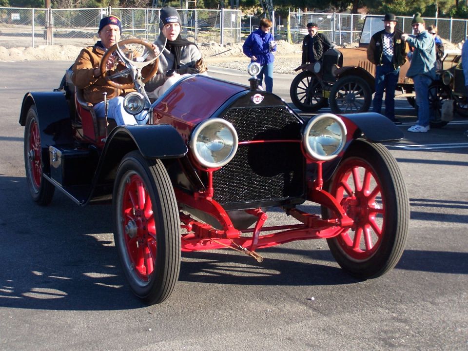 Red and black antique car front view with two occupants
