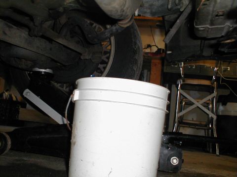 1997 Ford Crown Victoria - A white bucket is positioned under a vehicle's undercarriage to collect dripping fluid.