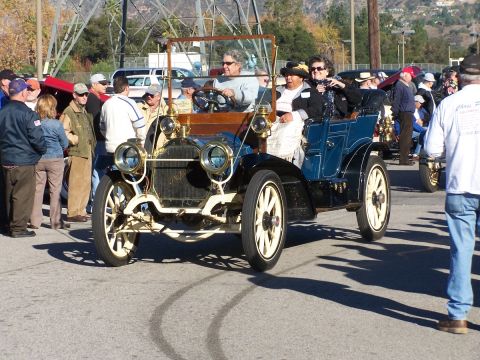 1990 Ford Bronco - An early 20th-century automobile is driven in a parade or car show with onlookers present.