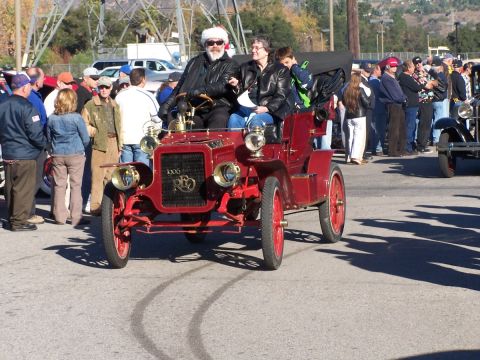 1990 Ford Bronco - A vintage red automobile, identified as a 1906 model, is the focus of attention at an outdoor event.